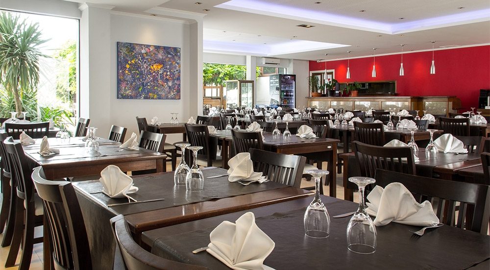 Comedor del restaurante con mesas puestas y una pared roja con cuadros