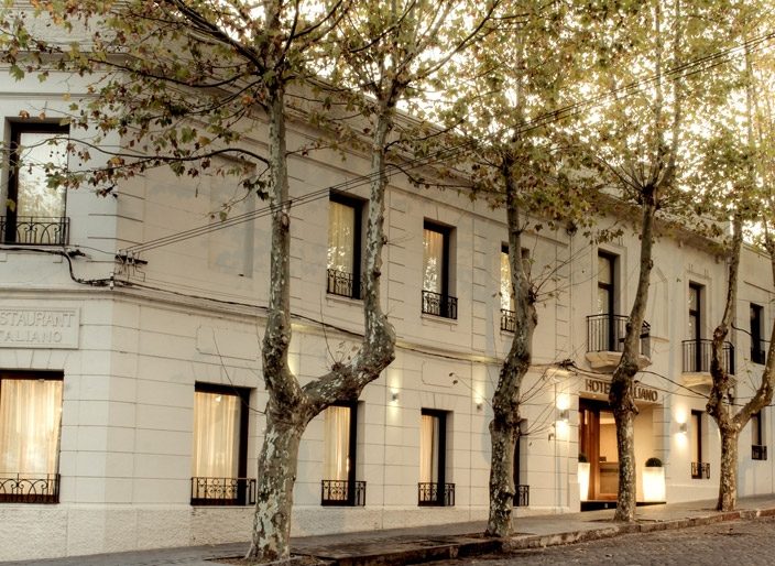 Fachada blanca del Hotel Italiano bajo los plátanos de la calle Intendente Suárez