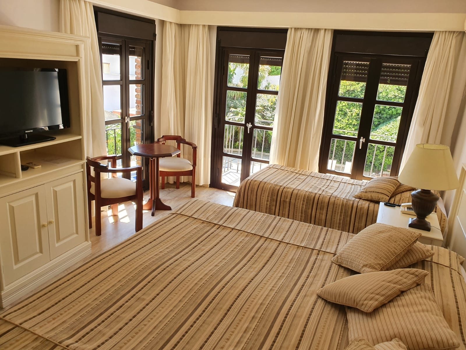Junior Suite con televisor, sillón y puerta ventana al balcón