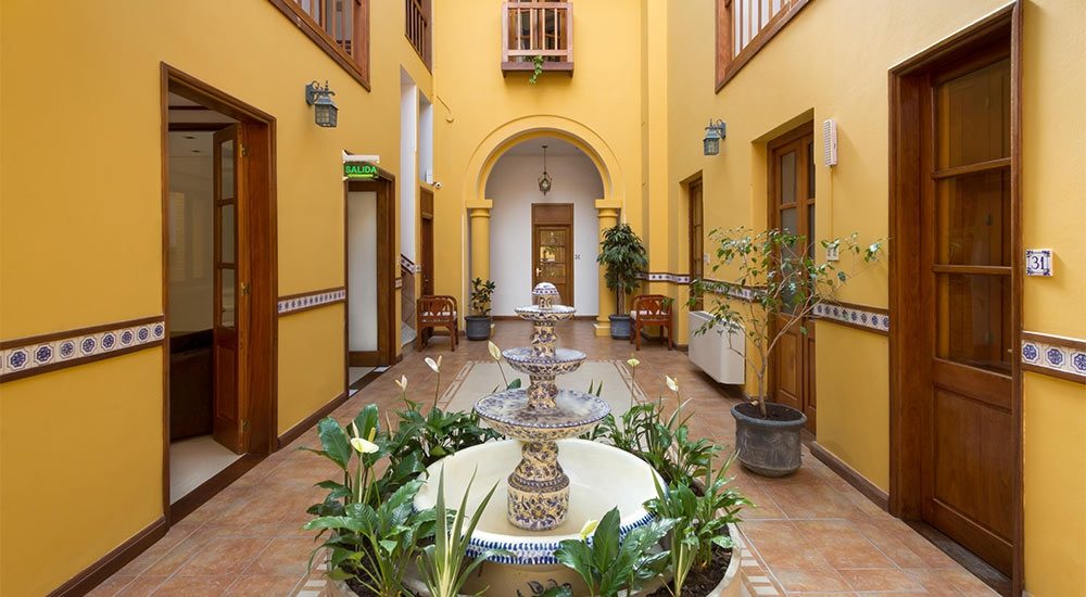 Patio interior colonial con fuente, paredes amarillas y galería